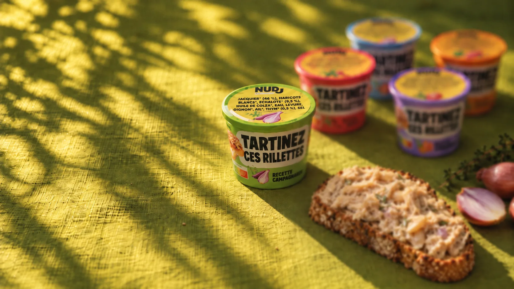 Les cinq rillettes Nudj sur une nappe verte au soleil, avec une tartine